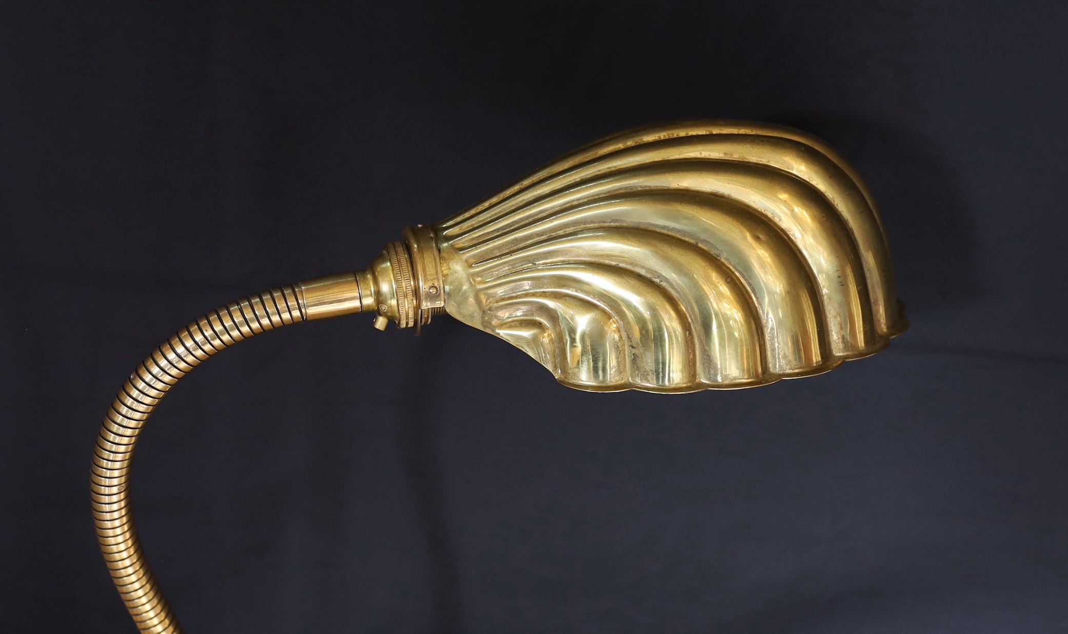 A 1930s English brass adjustable desk lamp, with flexible stem and scalloped shaped shade, height 58cm